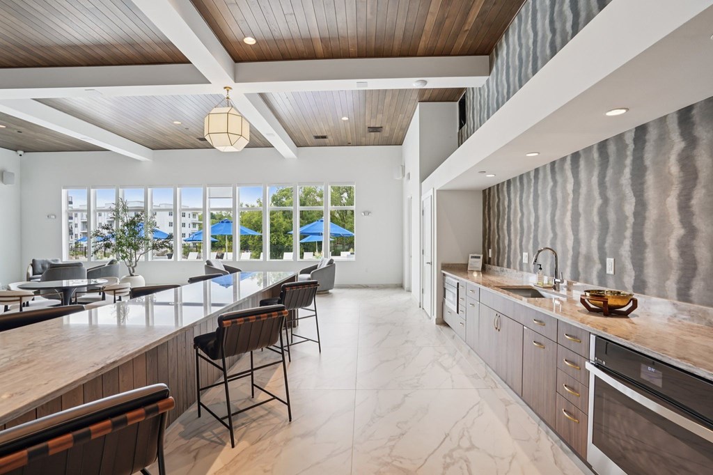A modern kitchen with a long counter and chairs.