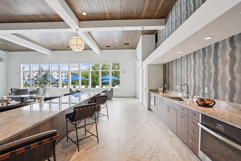 A modern kitchen with a long counter and chairs.