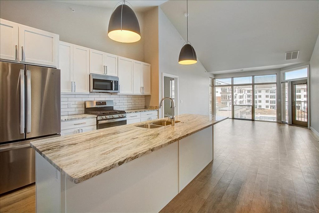 a kitchen with a large island and a stainless steel refrigerator