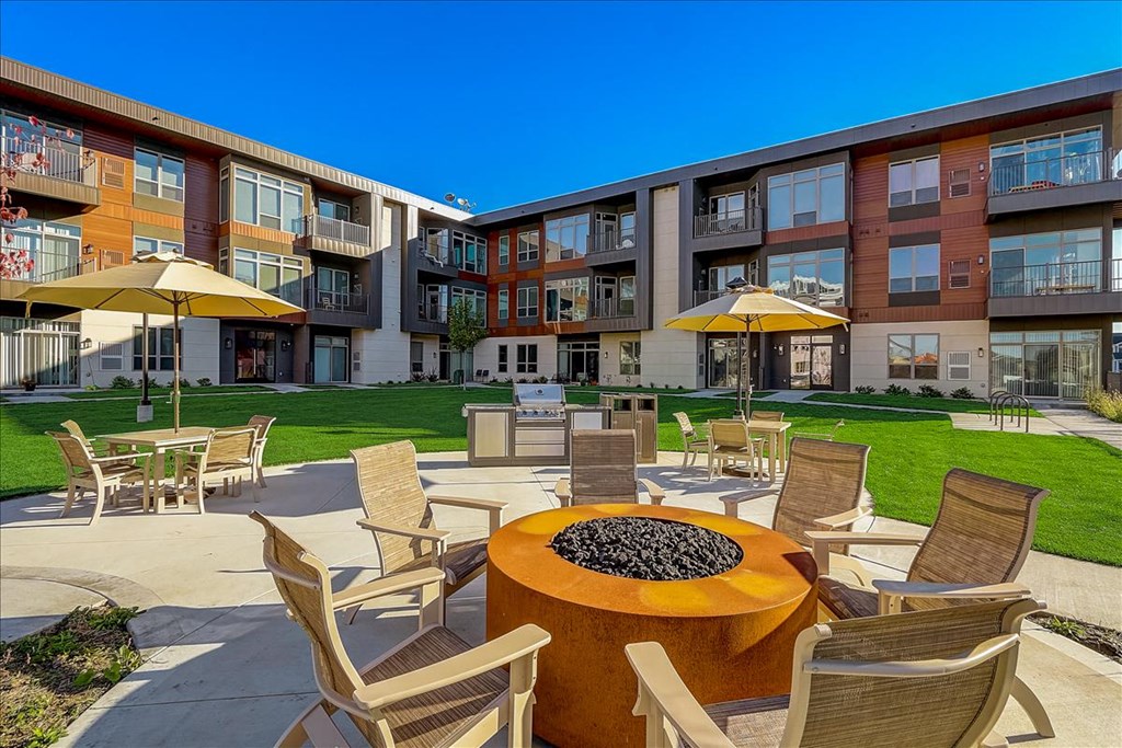 a patio with tables and chairs and a fire pit