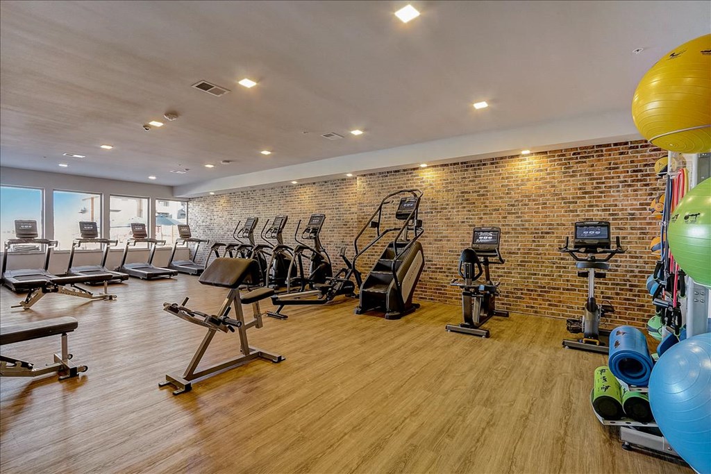 a gym with cardio equipment and a brick wall with balloons