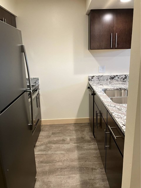 A kitchen with a black fridge and a marble countertop.