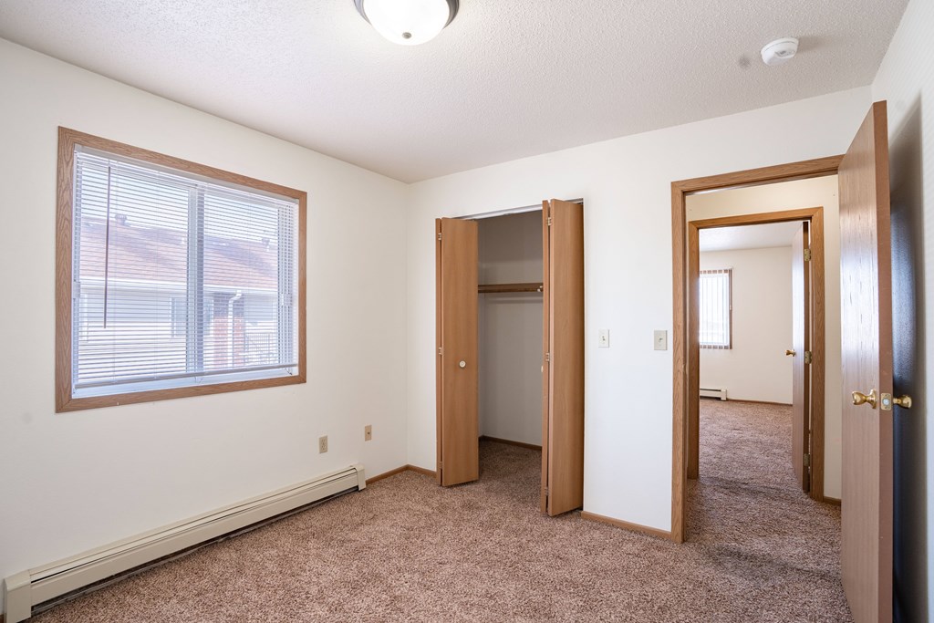 A room with a carpeted floor, a window, and a door.
