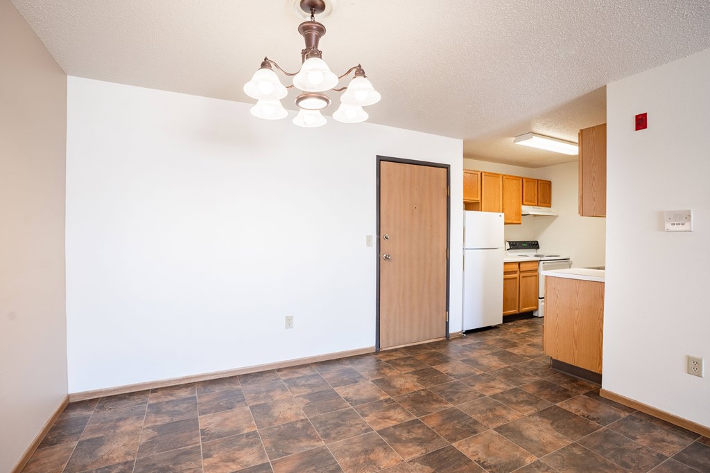 A kitchen with a refrigerator, sink, and wooden cabinets.