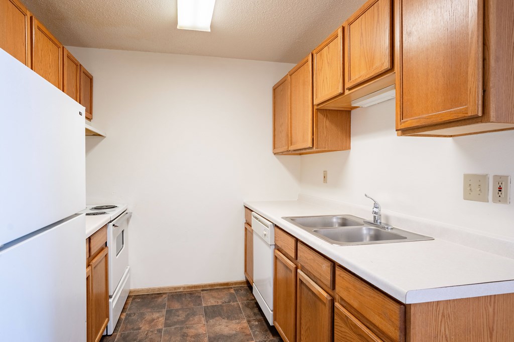 A kitchen with brown cabinets and a white fridge.