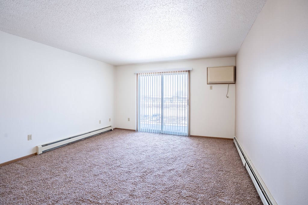 A room with a carpeted floor and a window with blinds.