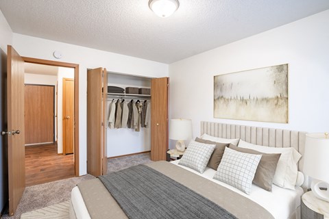 A bedroom with a large bed and a painting on the wall. Fargo, ND Candlelight Apartments