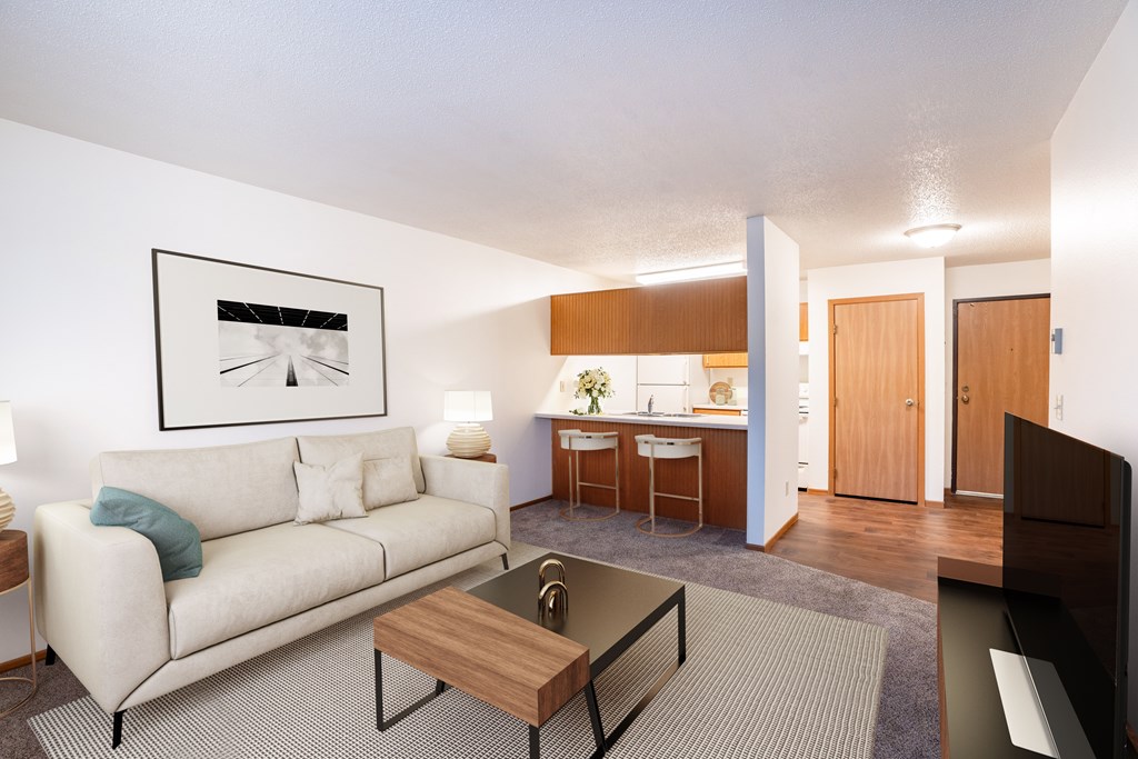 A living room with a couch, coffee table, and a painting on the wall. Fargo, ND Candlelight Apartments