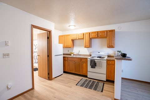 A kitchen with wooden cabinets and a white stove. Fargo, ND Candlelight Apartments