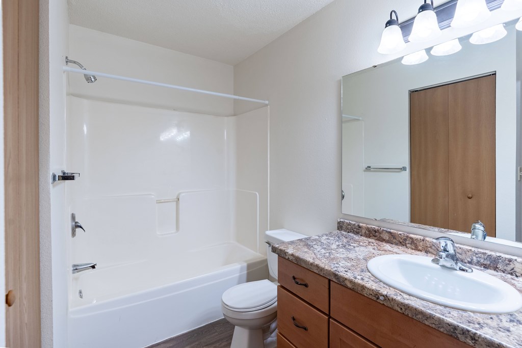 A white bathroom with a toilet, sink, and bathtub. Fargo, ND Country Edge Apartments