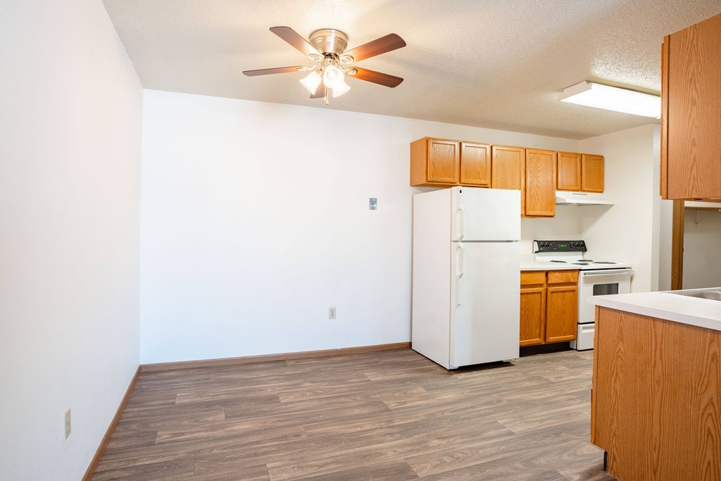 A kitchen with a white refrigerator and wooden cabinets. Fargo, ND Country Edge Apartments