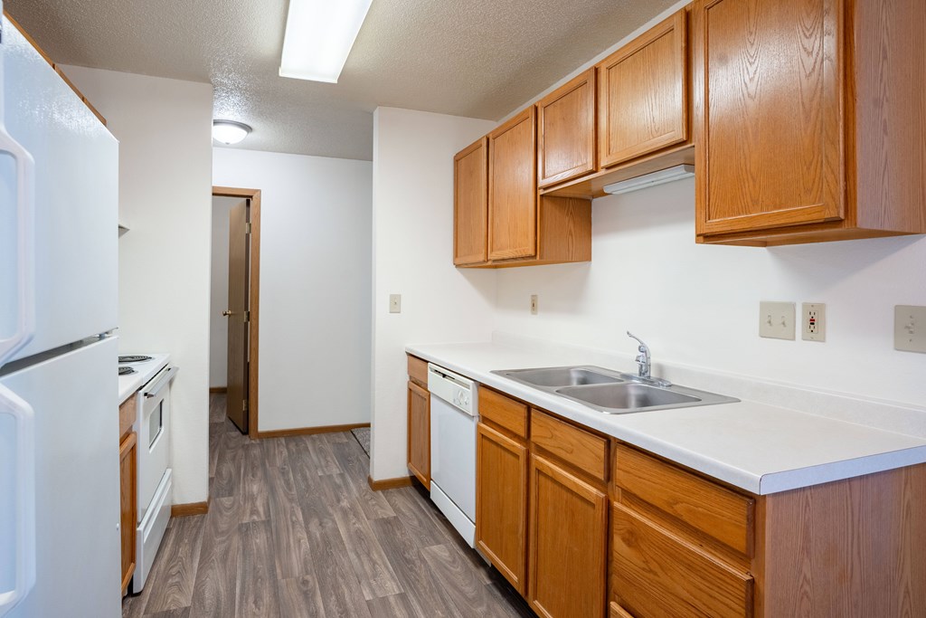 A kitchen with wooden cabinets and a white refrigerator. Fargo, ND Country Edge Apartments