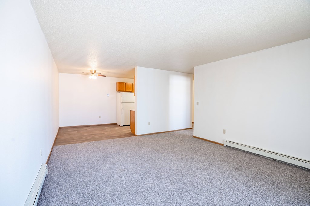 A room with a carpeted floor and a ceiling fan. Fargo, ND Country Edge Apartments