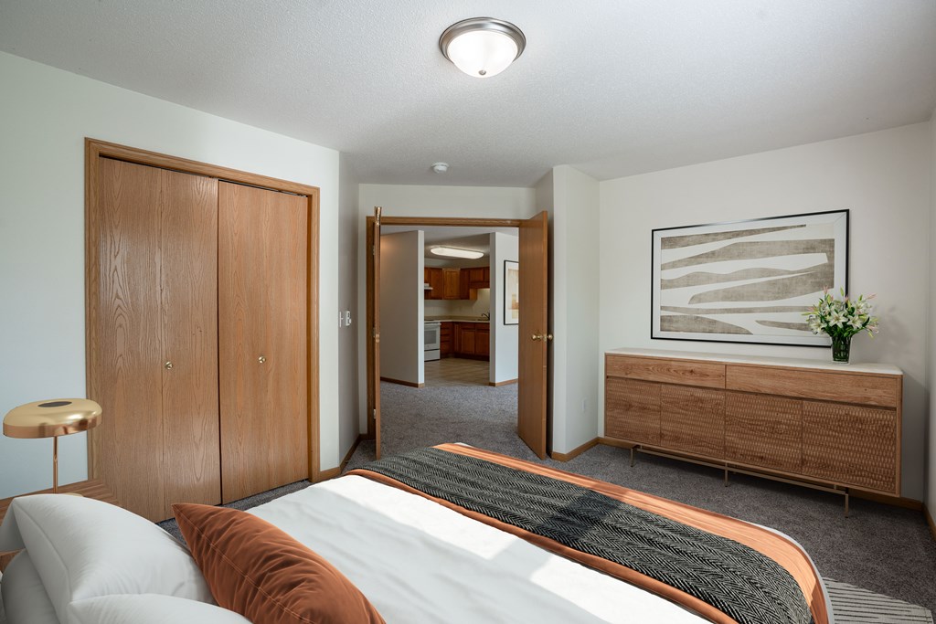 A bedroom with a bed, a dresser, and a painting on the wall.