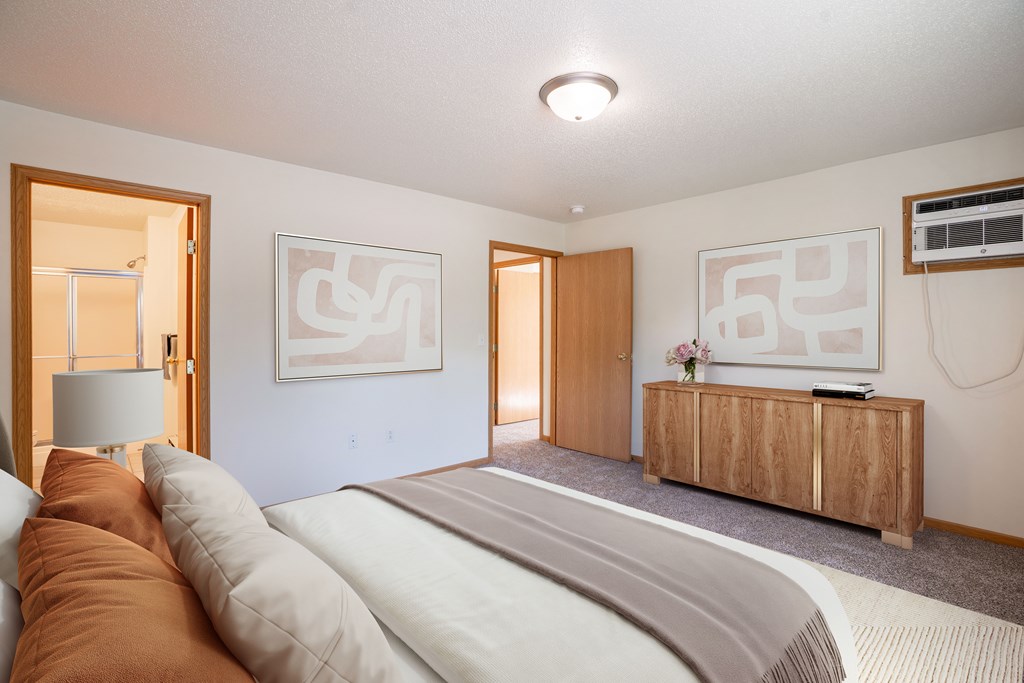 A bedroom with a large bed and two framed artworks on the wall.
