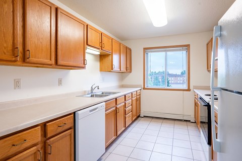 A kitchen with wooden cabinets and a white dishwasher.
