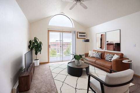 A living room with a brown couch, a television, and a plant. Fargo, ND Summit Point Apartments