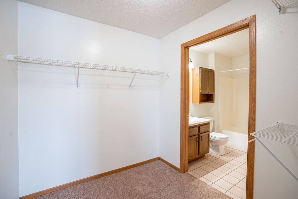 A white wall with a towel rack and a bathroom in the background. Fargo, ND Somerset Apartments