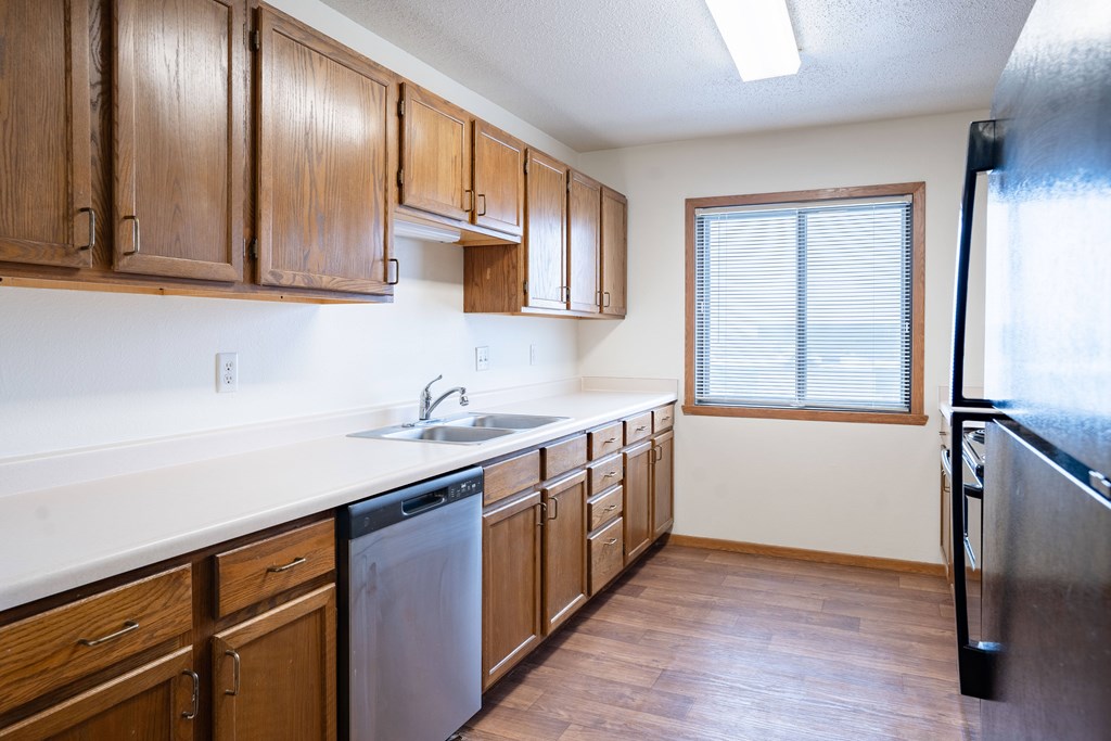 A kitchen with wooden cabinets and a dishwasher. Fargo, ND Somerset Apartments