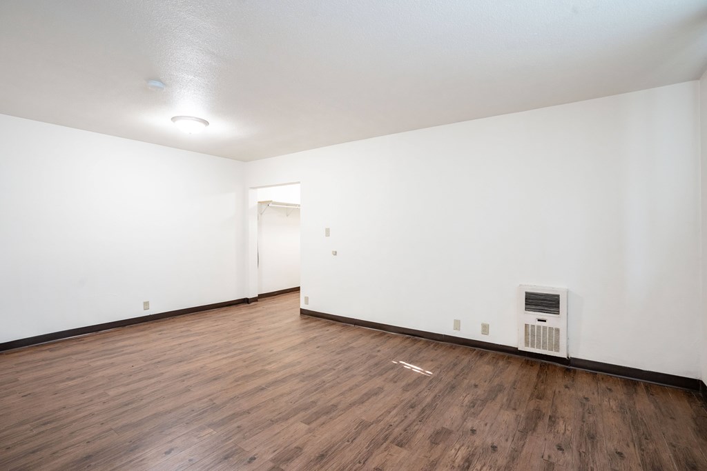 A room with a wood floor and a white wall. Fargo, ND L&R Apartments
