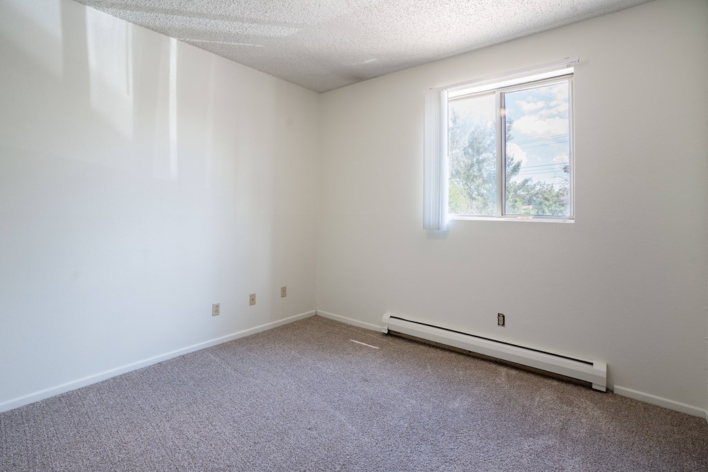 A room with a window and a radiator on the floor. Bismarck, ND Belmont Apartments