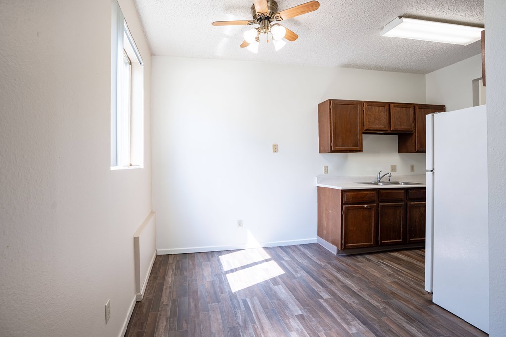 A kitchen with a white refrigerator and wooden floors. Bismarck, ND Belmont Apartments