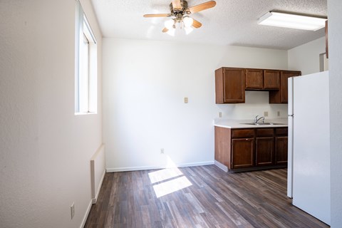 A kitchen with a white refrigerator and wooden floors. Bismarck, ND Belmont Apartments