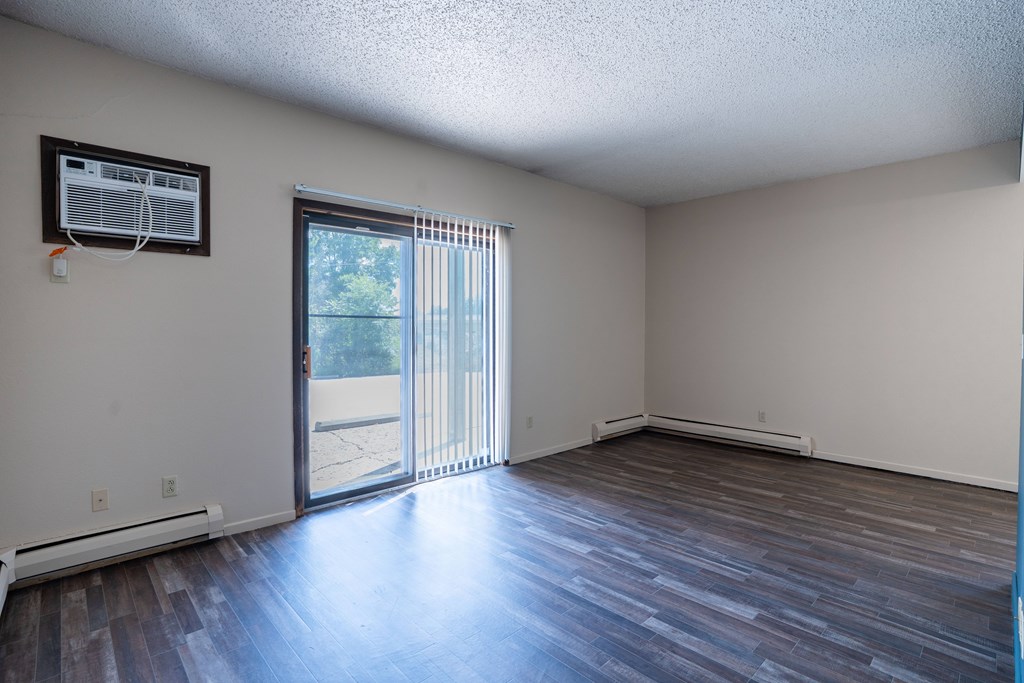 A room with a sliding glass door leading to a patio. Bismarck, ND Belmont Apartments