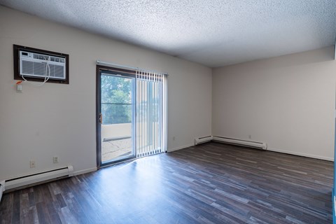 A room with a sliding glass door leading to a patio. Bismarck, ND Belmont Apartments