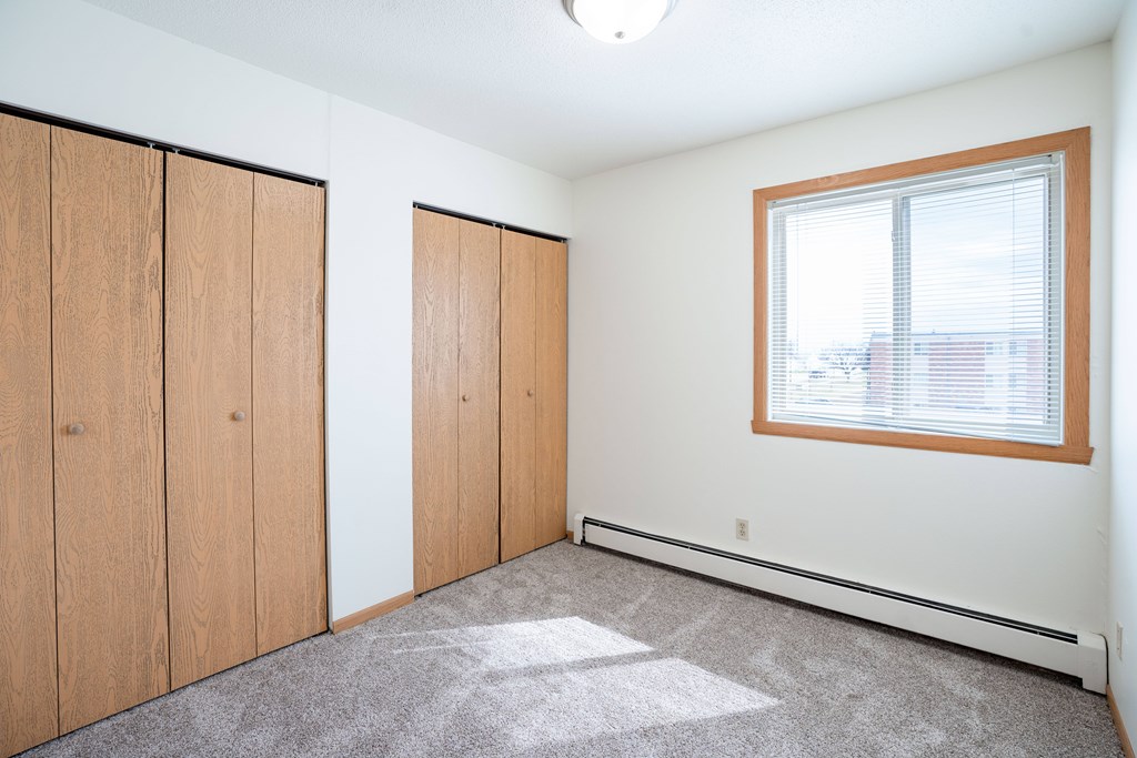A room with a window and a carpeted floor. West Fargo, ND Saddlebrook Apartments