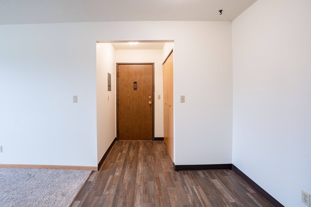 A room with a wooden door and floor. West Fargo, ND Saddlebrook Apartments