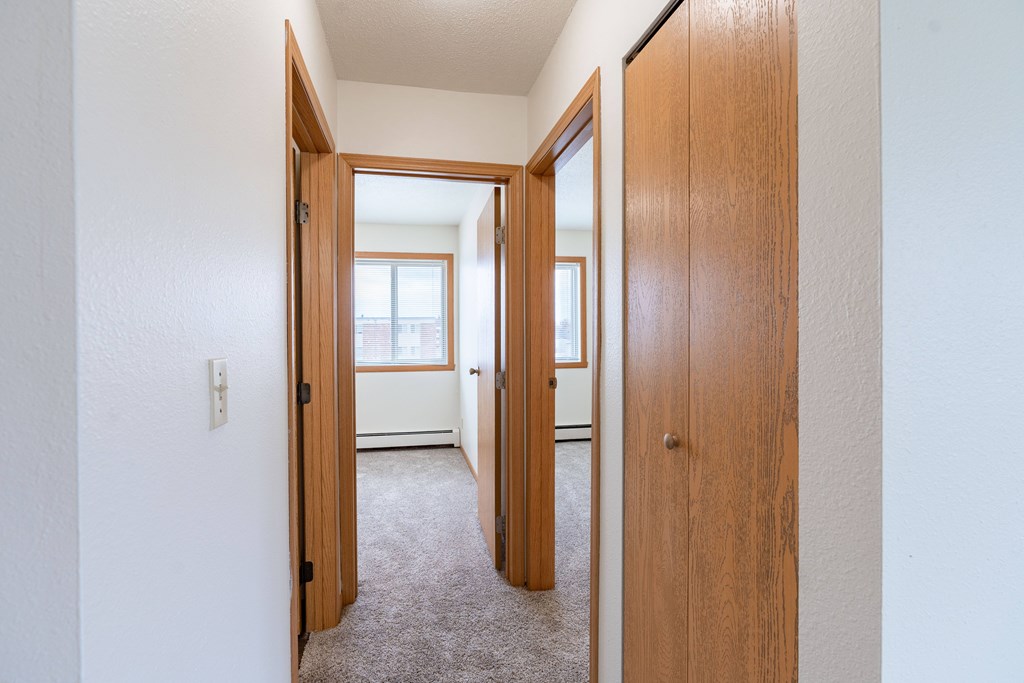 A hallway with two doors on either side leading to other rooms. West Fargo, ND Saddlebrook Apartments