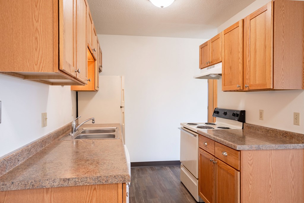 A kitchen with wooden cabinets and a granite countertop. West Fargo, ND Saddlebrook Apartments