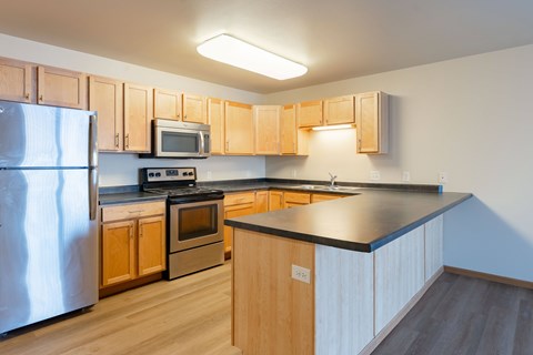 A kitchen with wooden cabinets and a black countertop.