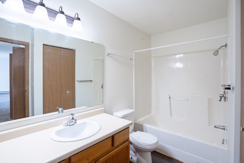 A white bathroom with a sink, toilet, and bathtub. Fargo, ND Fieldstone Apartments