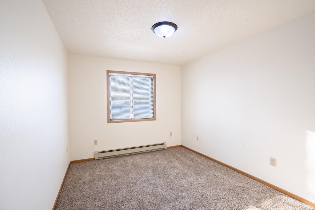 A room with a window and carpeted floor. Fargo, ND Fieldstone Apartments