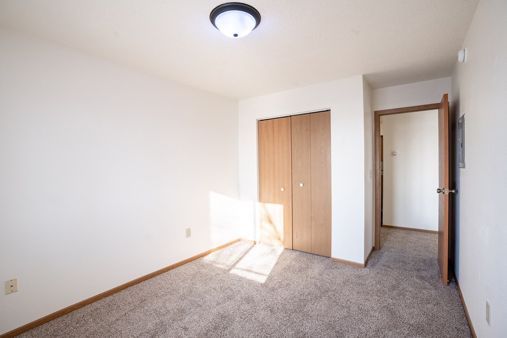 A room with a carpeted floor and a ceiling light. Fargo, ND Fieldstone Apartments