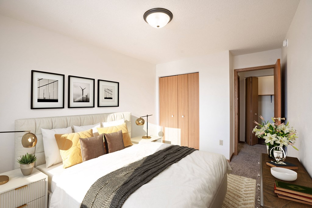 A bedroom with a large bed and a wooden door. Fargo, ND Fieldstone Apartments