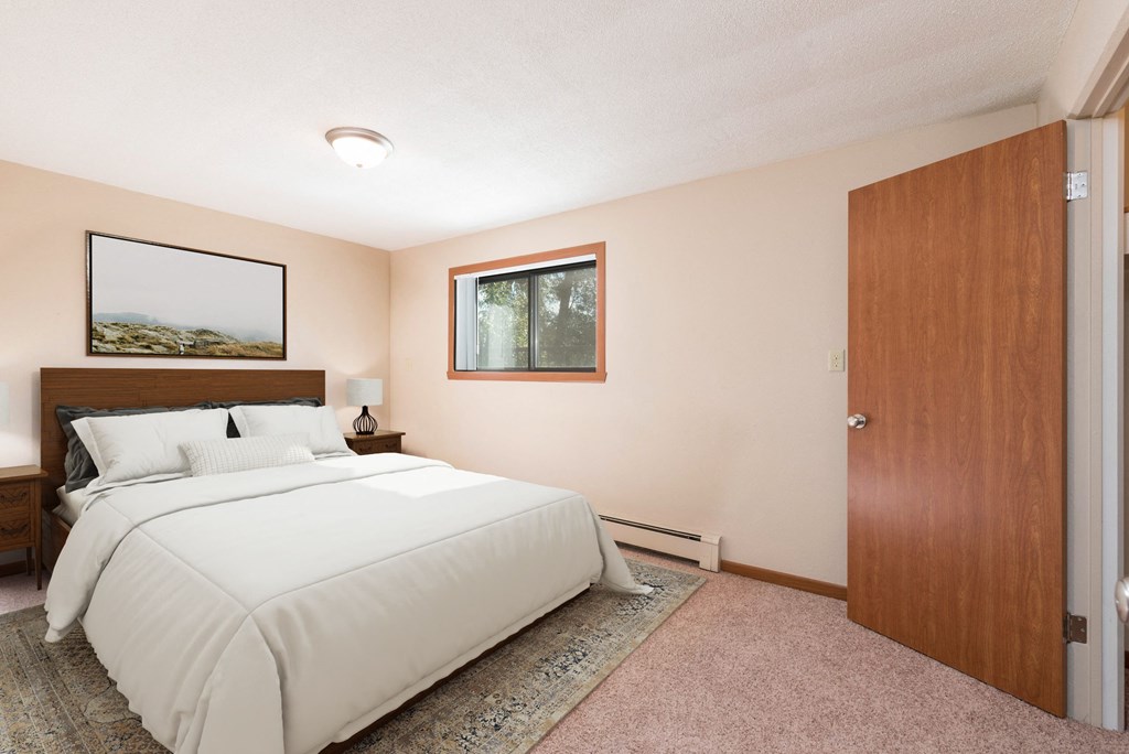 A bedroom with a large bed and a window. Bismarck, ND Parkview Arms Apartments