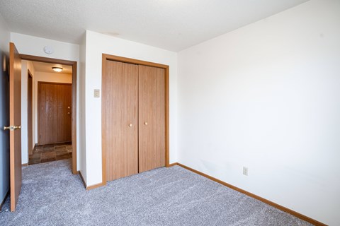 A room with a carpeted floor and a white wall. Fargo, ND Southgate Apartments
