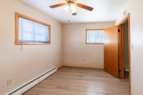 A room with a ceiling fan and two windows. Fargo, ND Birchwood Apartments