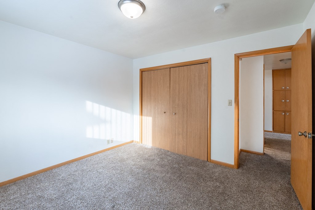 A room with two doors and a carpeted floor. Fargo, ND L&R Apartments