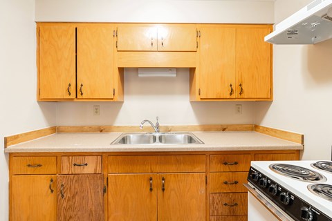 A kitchen with wooden cabinets and a white stove top oven.