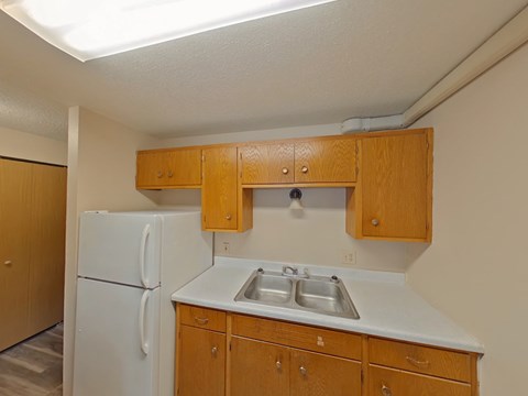 A kitchen with a white refrigerator and wooden cabinets.