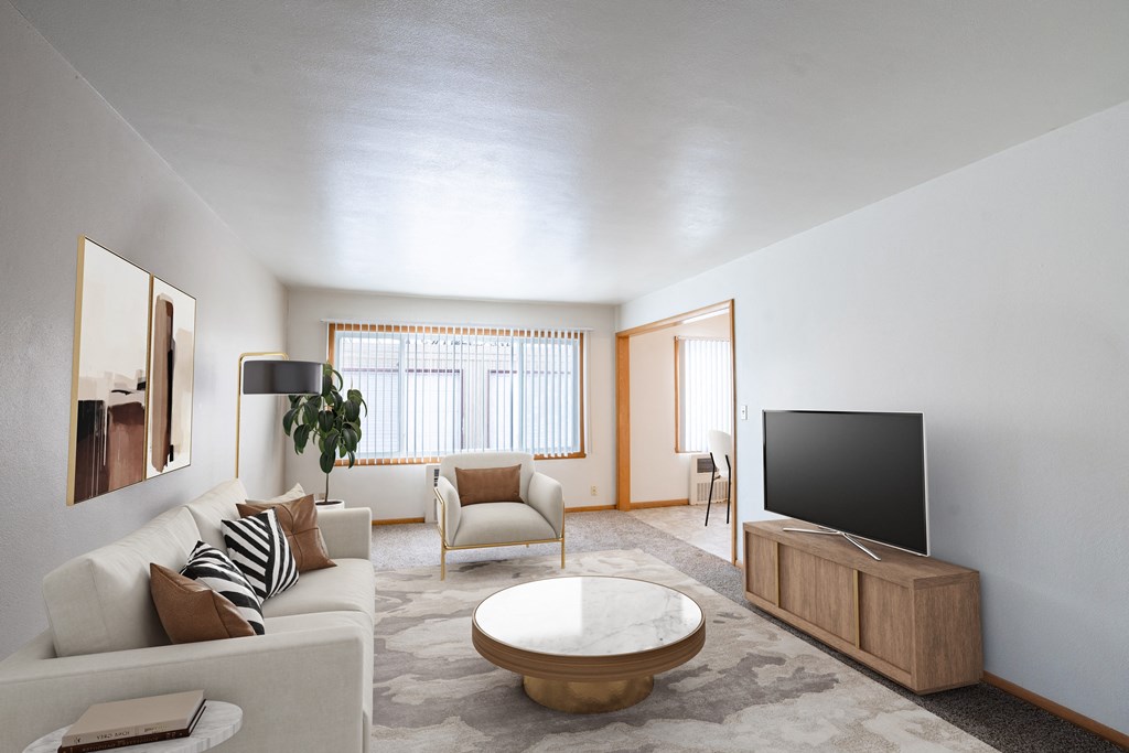 A modern living room with a white couch,  coffee table, and a television. Fargo, ND L&R Apartments