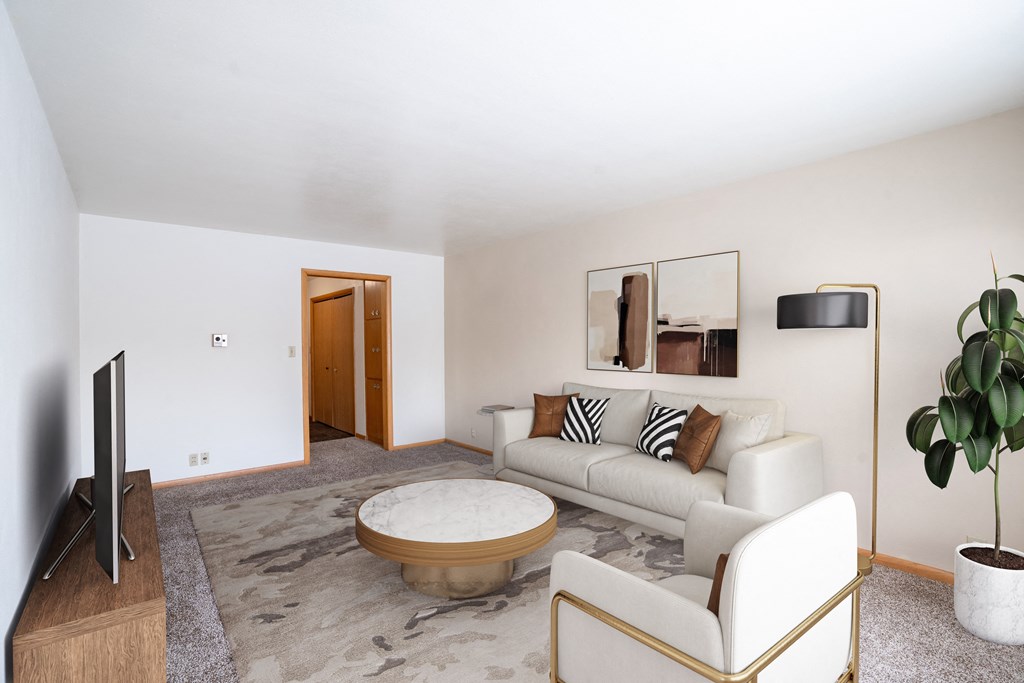 A living room with a white couch, a coffee table, and a television. Fargo, ND L&R Apartments