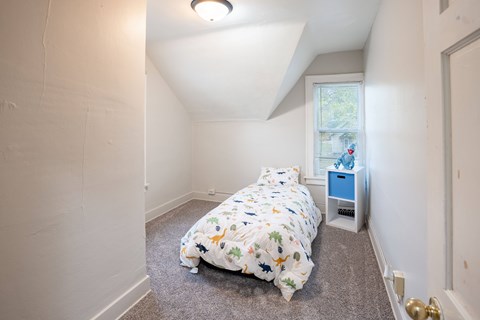 A bedroom with a bed, nightstand, and window.