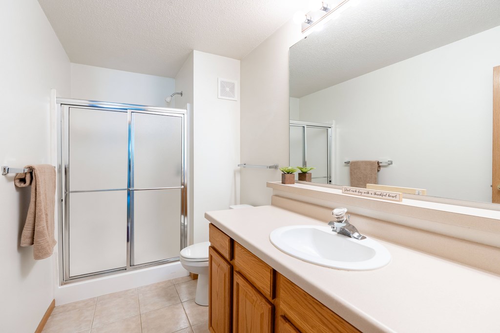 A bathroom with a sink, toilet, and shower. Fargo, ND Stonebridge Apartments
