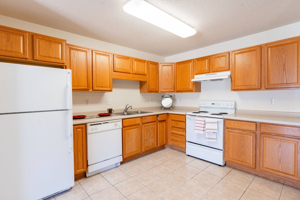 A kitchen with wooden cabinets and white appliances. Fargo, ND Stonebridge Apartments