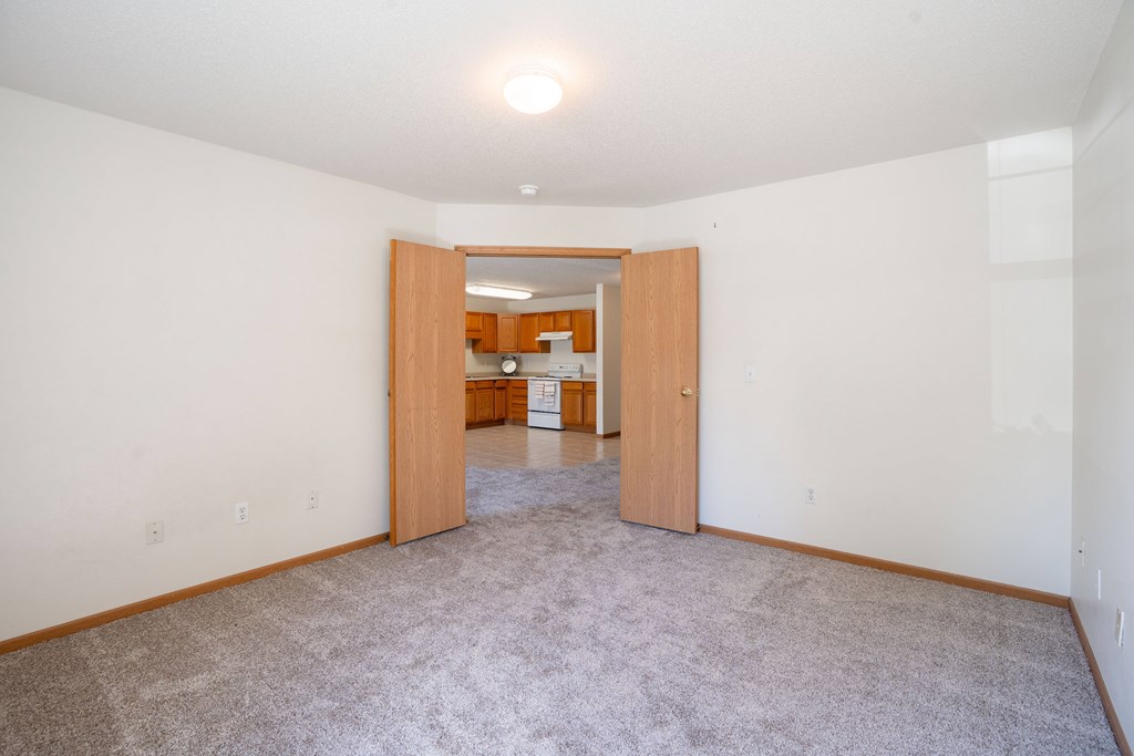 A room with a carpeted floor and a doorway leading to another room. Fargo, ND Stonebridge Apartments